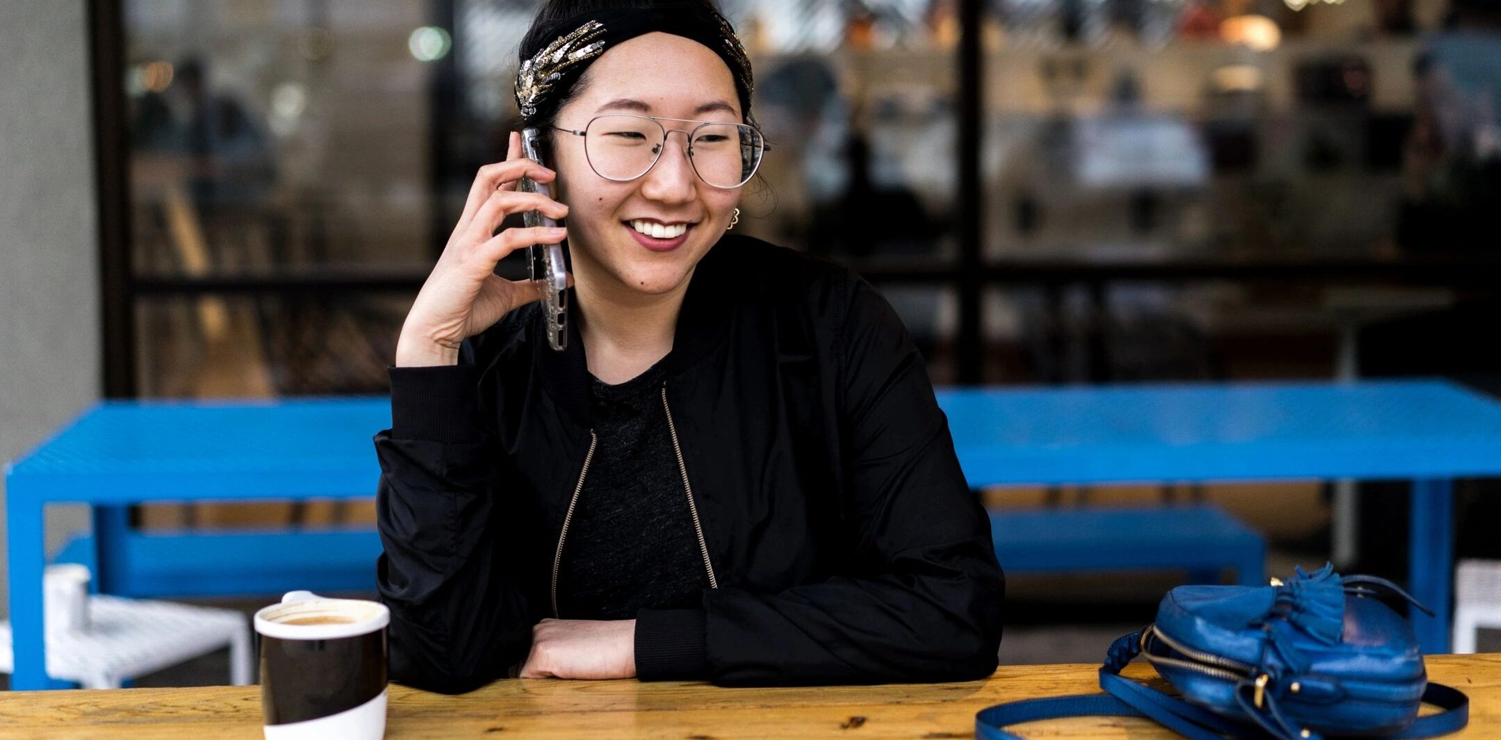 Smiling woman talking on the phone and drinking coffee at a restaurant