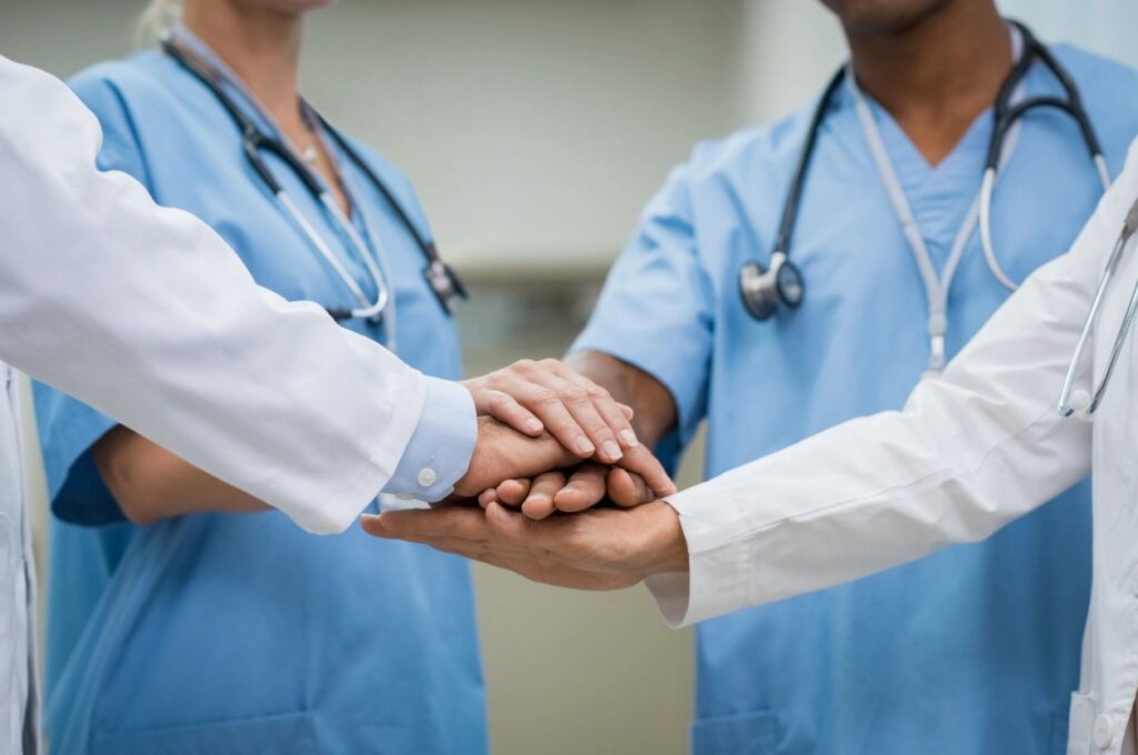 Healthcare professionals joining hands as a team.