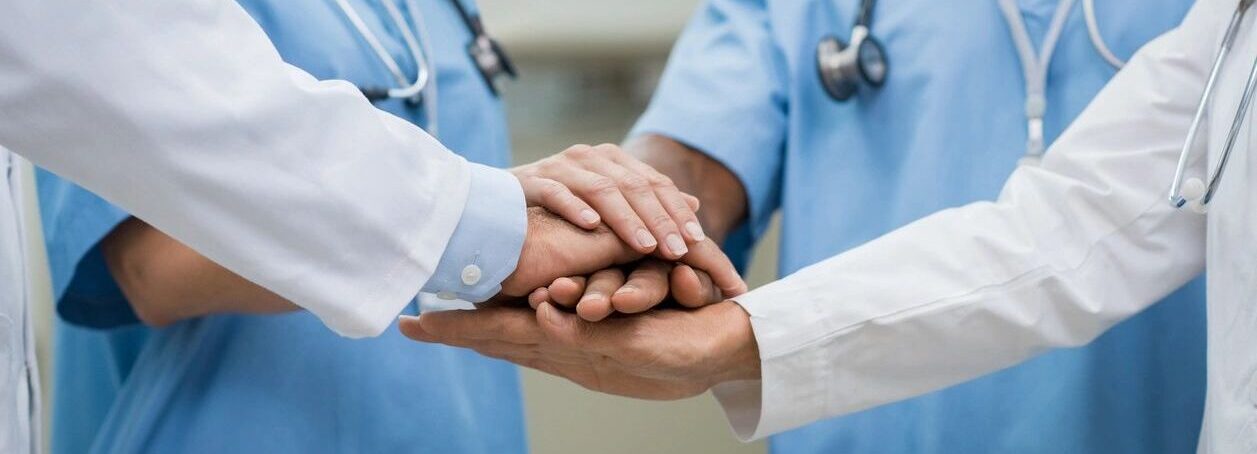 Medical professionals joining hands as a team.