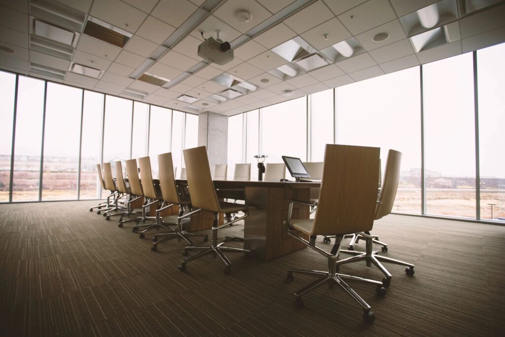 Empty board room with office table and chairs and large windows overlooking the town.