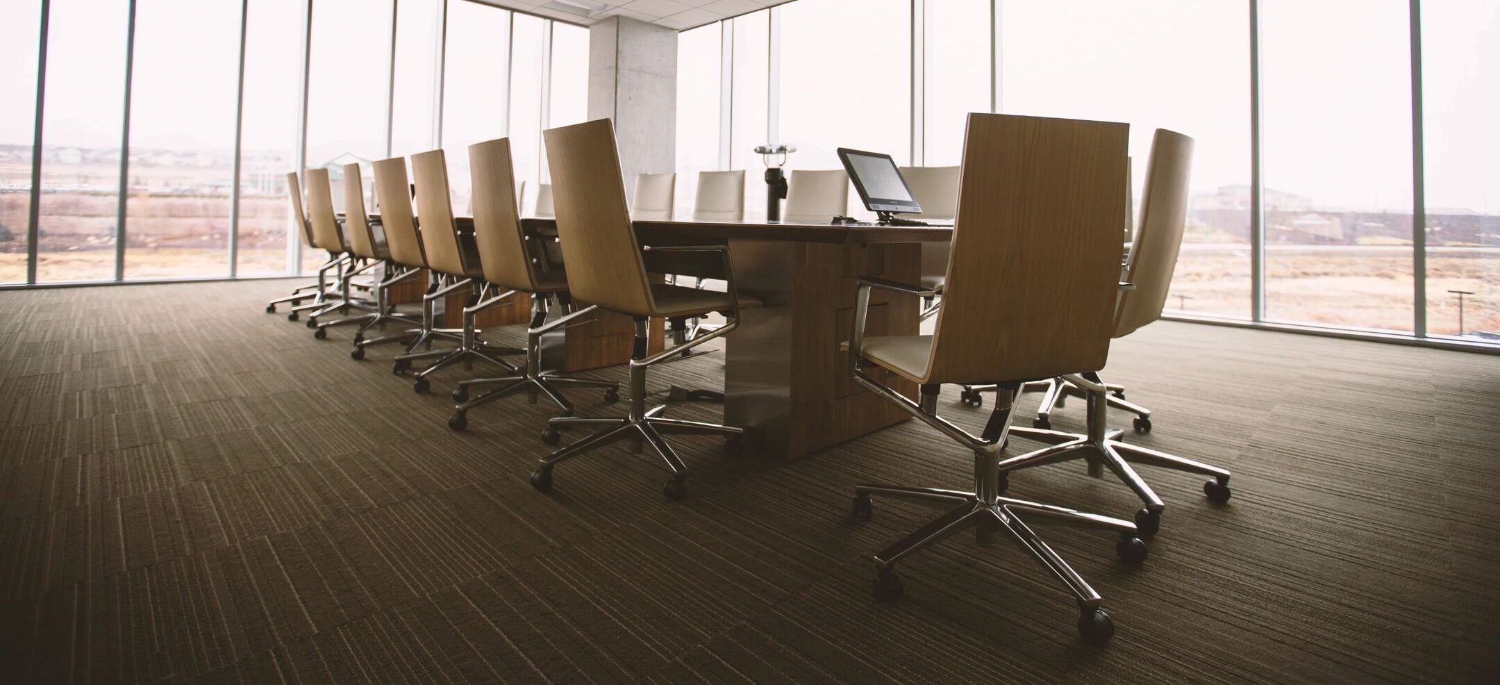 Office board room with table and chairs and large glass windows.