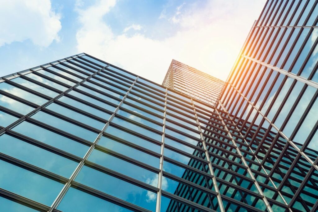 Skyscrapers with glass windows and metal frames, and sunlight reflecting on them.