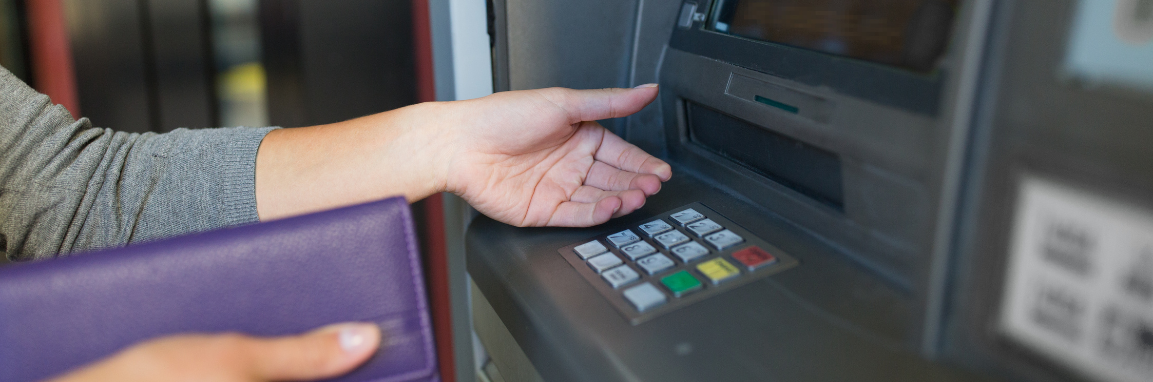 Atm machine with an open hand to receive cash and with a purple wallet.